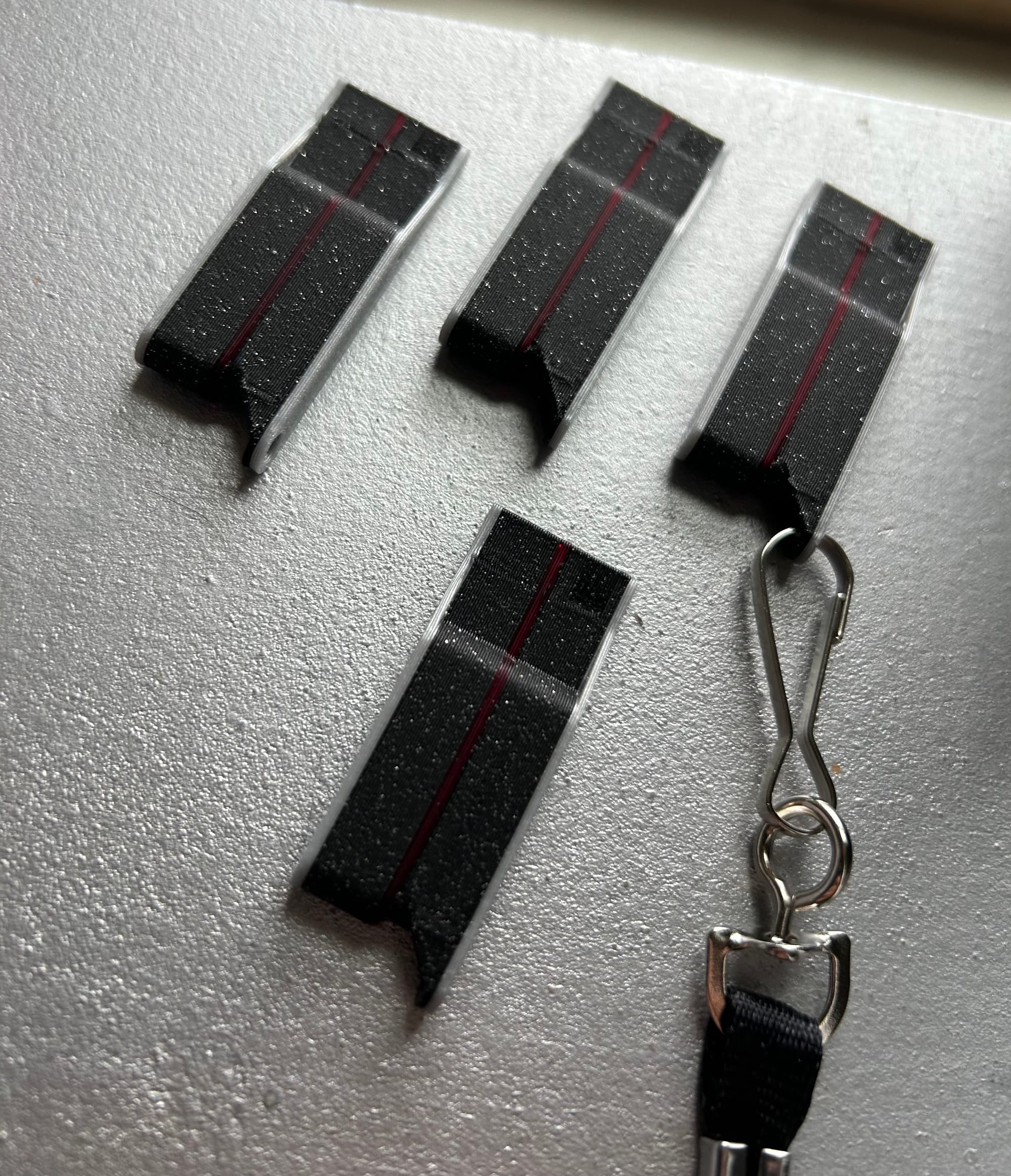 Four whistles with black bodies, grey trim and red stripes down the middle of each