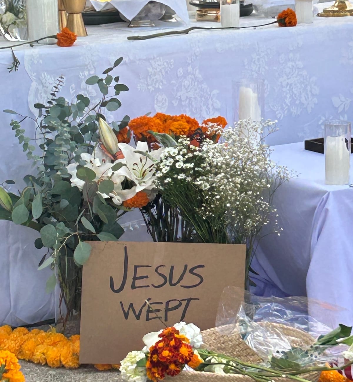 Image from a Mass said at the Broadview Detention Center in 2025; it depicts flowers and a sign that says Jesus Wept in front of an altar covered in white cloth.